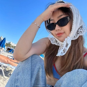 Outdoor close-up of a white lace bandana and black cat-eye sunglasses for beach style