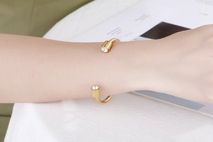 Close-up of golden open cuff bracelet with crystal cylinder ends on a female wrist