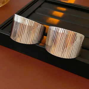 Macro shot of wide silver rings with vertical ribbed texture on black leather jewelry tray