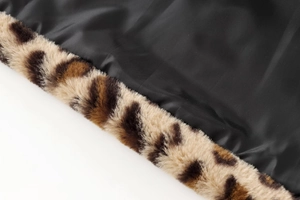 Detail of faux fur leopard print lapel stitched with black woven fabric on the coat