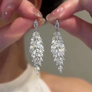 Close-up of silver leaf tassel earrings with sparkling cubic zirconia on a hand