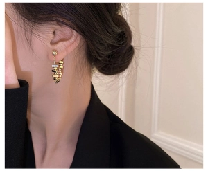 Detailed view of U-shaped gold geometric earrings with pavé crystals on a female model