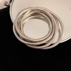 Detail of silver snake chain multi-layered stretch bracelets on reflective mirror surface