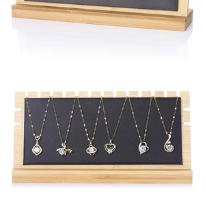 Close-up of bamboo jewelry stand with black velvet lining displaying gold necklaces