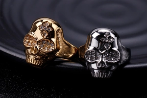 Close-up of gold and silver skull rings with crystal cross details on black tray