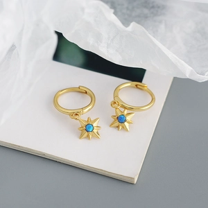Macro shot of gold star hoop earrings with round blue opal center on white background