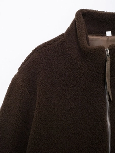 Close-up of textured dark coffee teddy fleece fabric and metal zipper detail