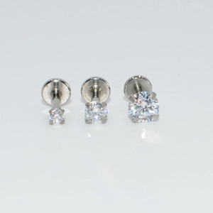 Primer plano de tres piercings de labio en acero inoxidable con circonitas brillantes