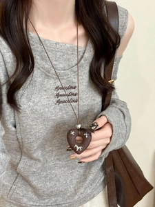 Detail of dark brown heart pendant with silver horse and flower charms on long necklace