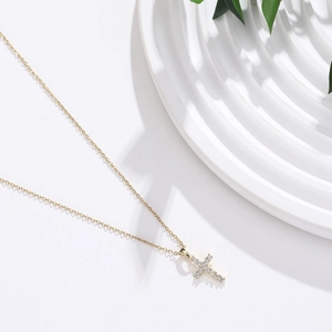 Minimalist gold stainless steel cross necklace with zircon stones on white display
