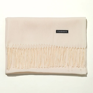 Detail view of beige cashmere scarf showing soft texture and official material tag