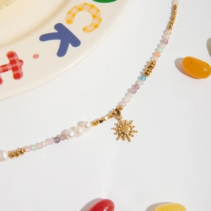 Detail of beaded necklace with freshwater pearls, colorful stones and sun charm