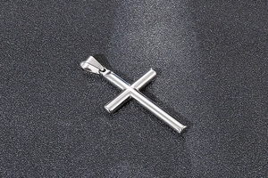 Pendentif croix en acier inoxydable poli sur un fond gris foncé texturé élégant