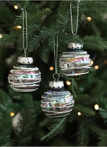 Close-up of deep green iridescent Christmas ornaments with snow powder patterns on tree