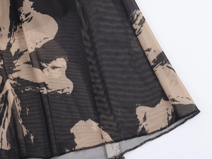 Close-up of lightweight black mesh fabric with abstract beige ink prints and ruffled hem