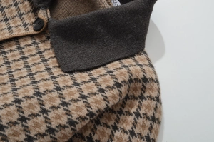 Detail der Stricktextur und des braunen Hahnentrittmusters auf einer Strickjacke mit Kragen