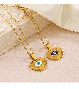 Detailed shot of gold heart necklaces with blue evil eye pendants on stone and silk