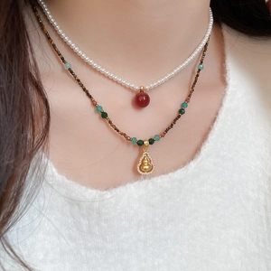 Close-up of double-layer necklace with pearl, tiger eye beads and zircon gourd pendant