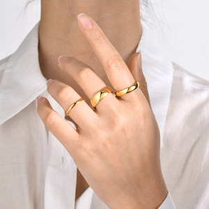 Detailed view of three polished gold stainless steel rings with varying band widths