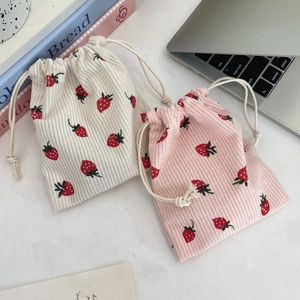 Flat lay of corduroy drawstring storage bags with strawberry print on a desk