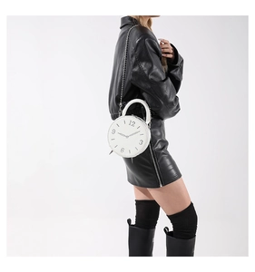Détail d'un sac à main blanc en cuir en forme d'horloge avec chiffres noirs et chaîne métal