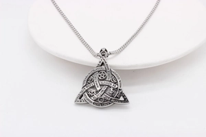Macro detail of Viking Trinity knot pendant with mystical symbols and engraved mottos