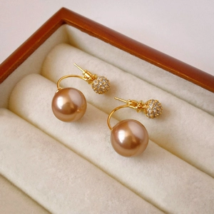 Detail of vintage gold-plated earrings with champagne pearls and sparkling zircons