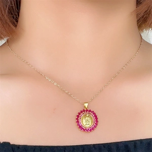 Close-up of Virgin Mary pendant necklace with radiant gold halo and red zircon stones