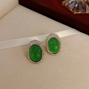 Gros plan de boucles d'oreilles vintage dorées avec pierres vert émeraude et zircons