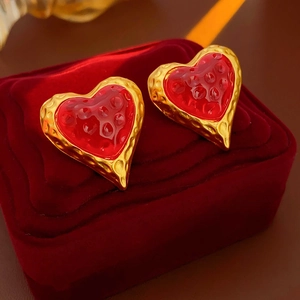 Detailed macro view of vintage gold heart earrings with red textured center in a velvet box