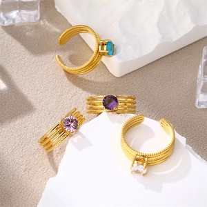 Detail shot of four gold-plated stainless steel rings with colorful round zircon stones