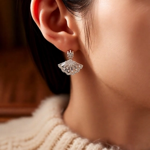 Macro detail of silver fan-shaped drop earrings with sparkling pavé zircons on model