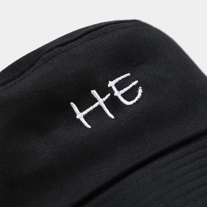 Gros plan de la broderie HE sur un chapeau bob en coton noir avec des coutures fines
