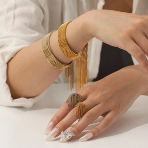 Detailed view of dual-tone tassel bracelets and rings with textured metallic finish