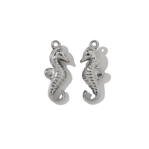 Detailed close-up of two silver seahorse pendants in stainless steel with carved textures