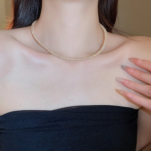 Detail of champagne gold mesh necklace featuring shimmering zircons on a model's collarbone