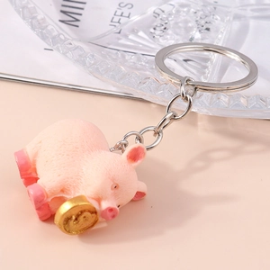 Cute pink pig resin keychain with gold coin charm on elegant textured glass background