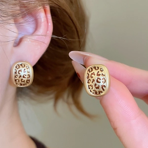 Close-up of vintage golden leopard print earrings with a polished metallic border