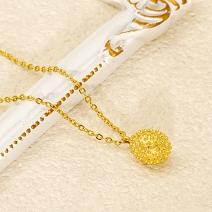 Macro view of gold durian-shaped stainless steel pendant with textured details