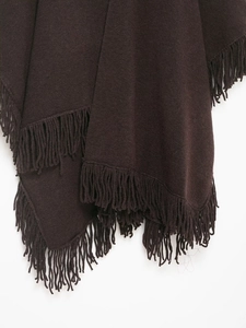 Close-up of deep brown knitted poncho fabric with dense fringe details and texture
