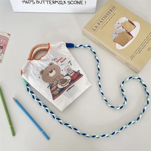 Détail du mini sac blanc avec broderie d'ours et bandoulière tressée tricolore élégante