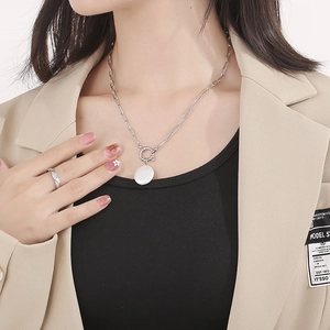 Silver stainless steel paperclip chain necklace with round pendant and textured ring on model