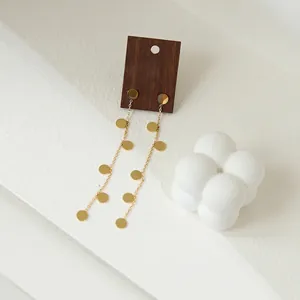 Minimalist long 18K gold plated titanium drop earrings with polished round sequins on a stand