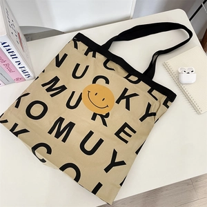 Detailed close-up of large canvas tote bag with smiley face icon and letter print pattern