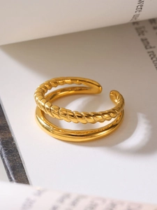 Macro detail of 18k gold plated double-layer twisted and smooth open ring on white book