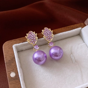 Detail of luxury purple crystal and faux pearl earrings in a beige velvet jewelry box