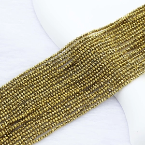 Macro shot of 2mm faceted golden beads on white background for DIY jewelry making
