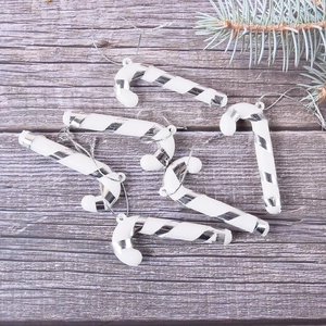 Detail of six white and silver plastic candy cane ornaments on rustic wood background