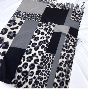 Detail of leopard print and color-block scarf featuring soft tassels and knit texture