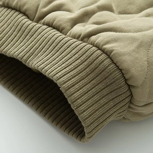 Détail macro des poignets en tricot côtelé et texture matelassée de la veste pilote